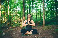 Woman doing prayer pose in forest