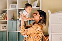 Mother holding up baby son in nursery