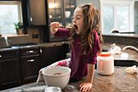 Little girl eating on kitchen worktop