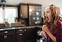 Little girl eating on kitchen worktop