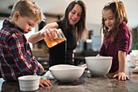 Children watching mother pour honey into bowl