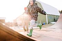 Boy with father running on sunlit farmyard skatebo