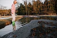 Boy ankle deep in rural puddle, portrait