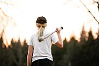 Girl with baseball bat over her shoulder in rural 