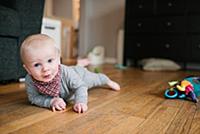 Baby boy crawling on wooden floor