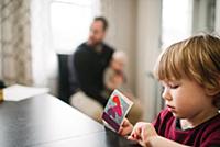 Boy playing at table, father in background