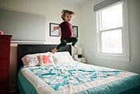 Boy jumping on bed