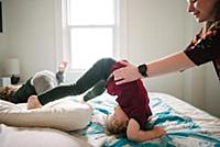 Mother helping son tumble in bed