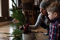 Mother and children creating potted leaf arrangeme