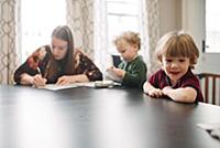Mother filling form with sons playing at table