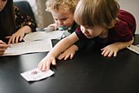 Mother filling form with sons playing at table