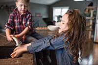 Toddler helping sister wash hands in kitchen sink