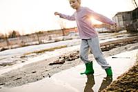 Boy playing in rural meltwater puddle