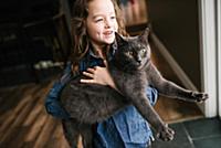 Little girl playing with cat at home