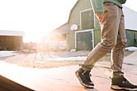 Man walking across farmyard skateboard ramp, waist