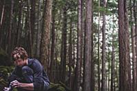Climber taping fingers before bouldering in forest