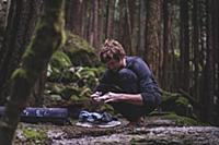 Climber taping fingers before bouldering in forest