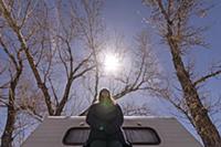 Woman beside campervan, bare trees in background