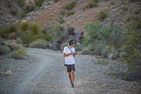 Man walking along dirt track operating drone (unma