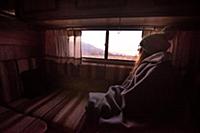 Woman keeping warm inside campervan in desert, Sie