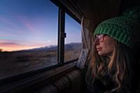 Woman keeping warm inside campervan in desert, Sie
