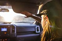 Woman passenger in front seat of car shielding eye
