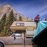 Climber on top of campervan setting up tent, Yosem