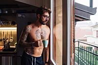 Mid adult man with tattoos looking out through kit