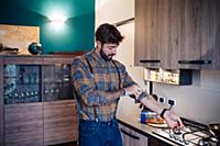 Mid adult man in kitchen rolling up shirt sleeve