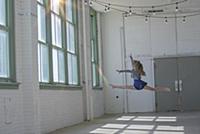 Teenage girl with long brown hair leaping mid air 