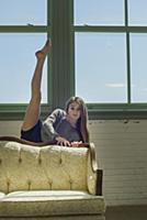 Teenage girl in dance studio behind sofa with leg 