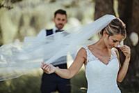 Bride and groom holding delicate wedding veil in w