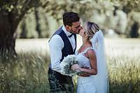 Romantic bride and groom kissing in woodland