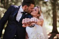 Romantic bride and groom kissing and showing weddi