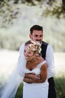 Romantic groom hugging bride from behind in woodla