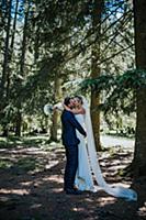 Romantic groom lifting up bride to kiss in woodlan