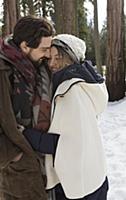 Young woman and boyfriend hugging in winter forest