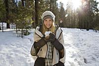 Young woman holding snowball in winter forest, por