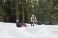 Young woman pulling boyfriend on sledge in winter 