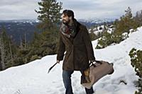 Mid adult man carrying logs and axe on snow covere