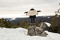 Young woman standing on rock on snow covered mount