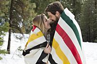 Young woman and boyfriend wrapped in blanket toget