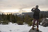 Mid adult man photographing view from rock on snow