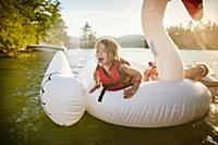 Girls playing on inflatable swan in lake