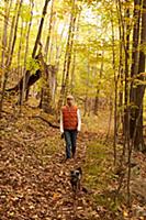 Woman walking dog in woods