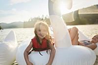 Girls playing on inflatable swan in lake