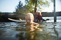 Girl swimming and playing in lake, father and sist