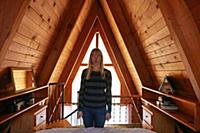 Woman making face in bedroom in A-frame house