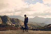 Woman walking dog on hilltop, Big Bear Lake, Calif