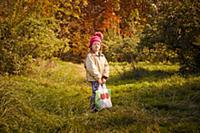 Girl with bag of fresh picked apples in orchard